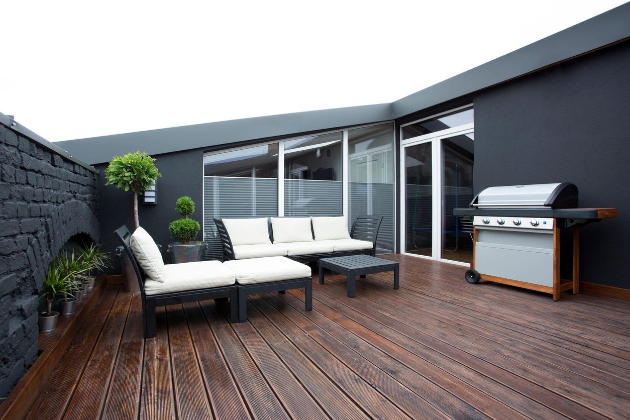 A wooden deck with furniture and a grill on it.