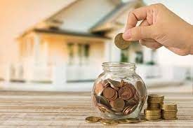 A person is putting coins into a glass jar.