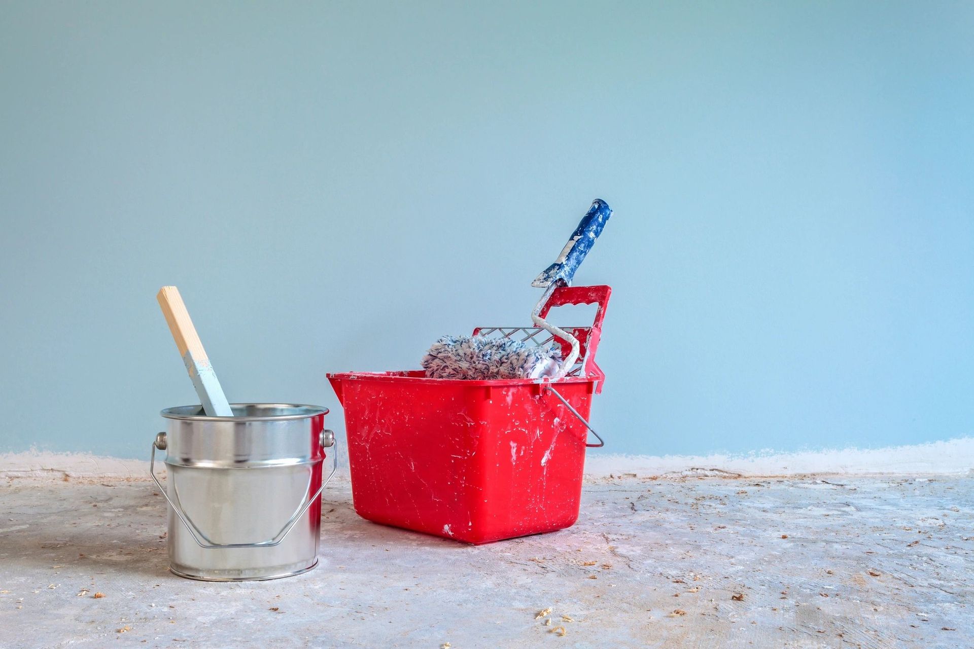 There is a bucket of paint and a roller on the floor.