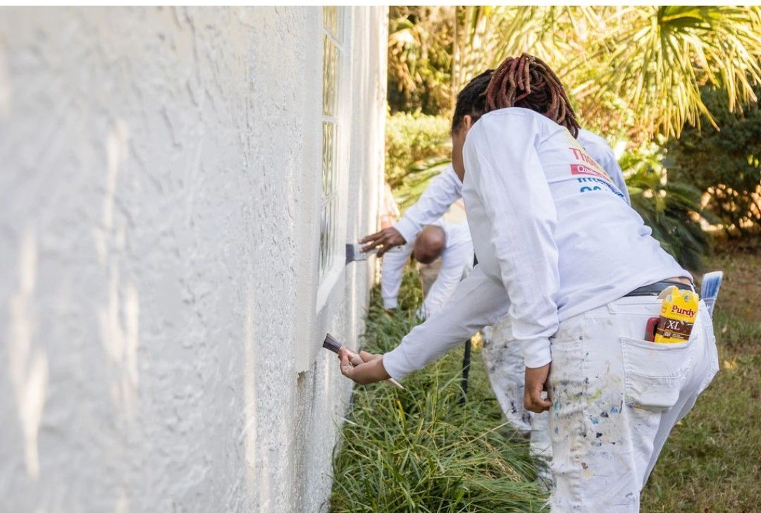 A group of people are painting a white wall.