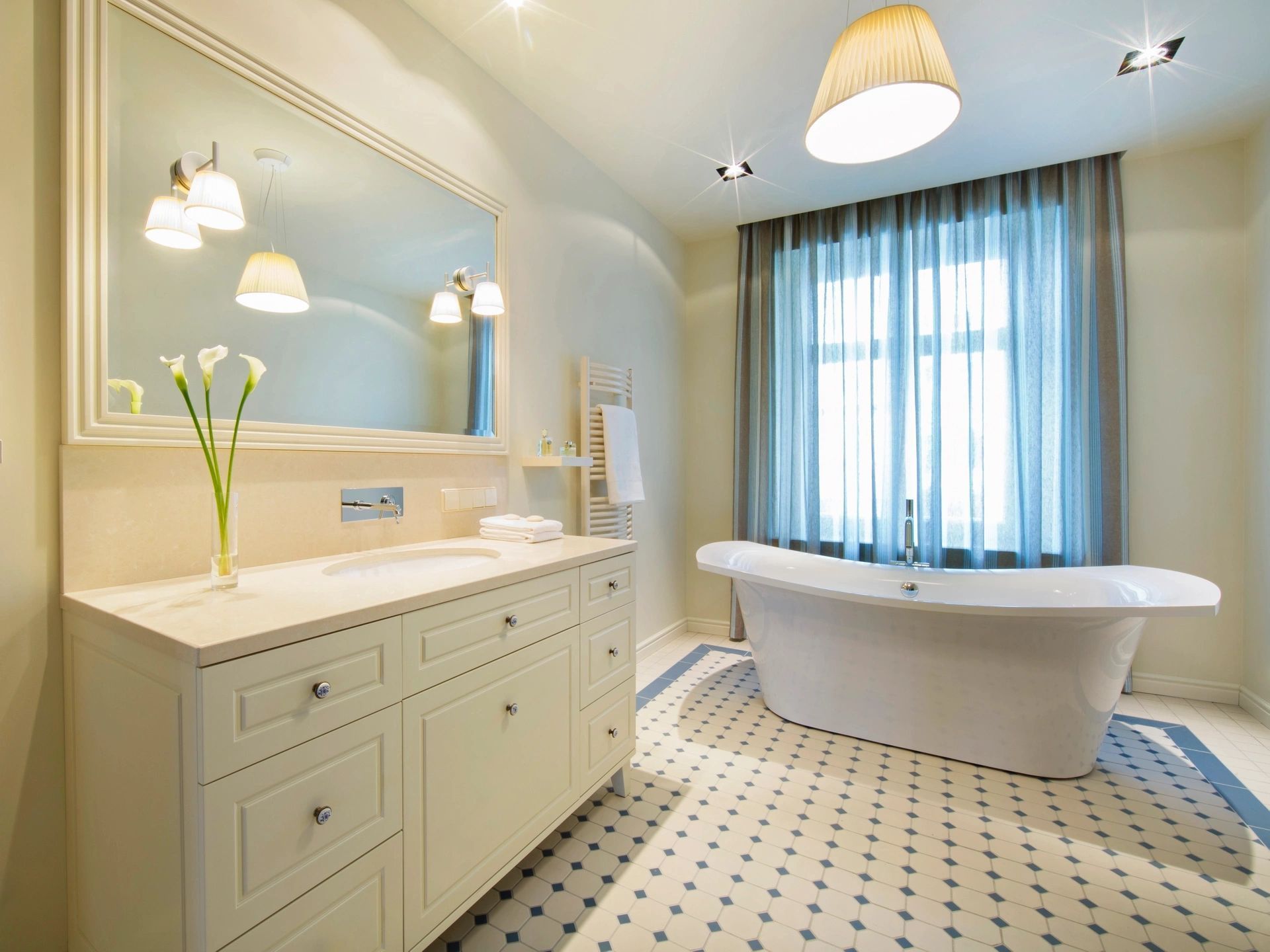 A bathroom with a tub , sink , mirror and window.