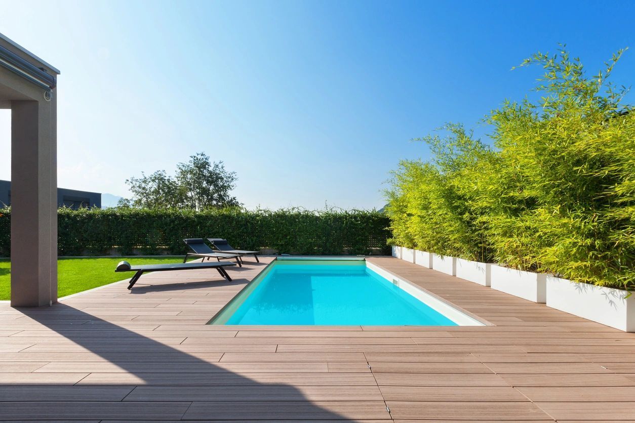 A swimming pool with a wooden deck in the backyard of a house.