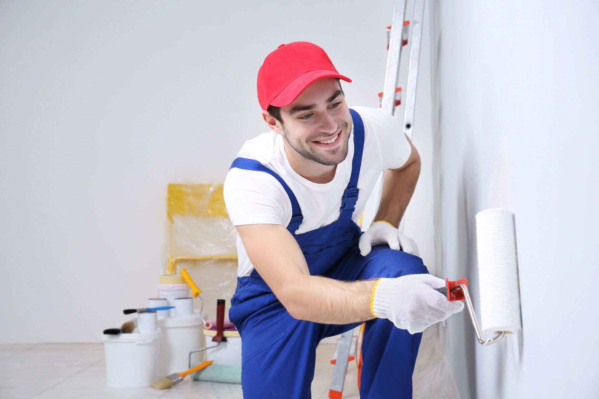 A man is painting a wall with a paint roller.