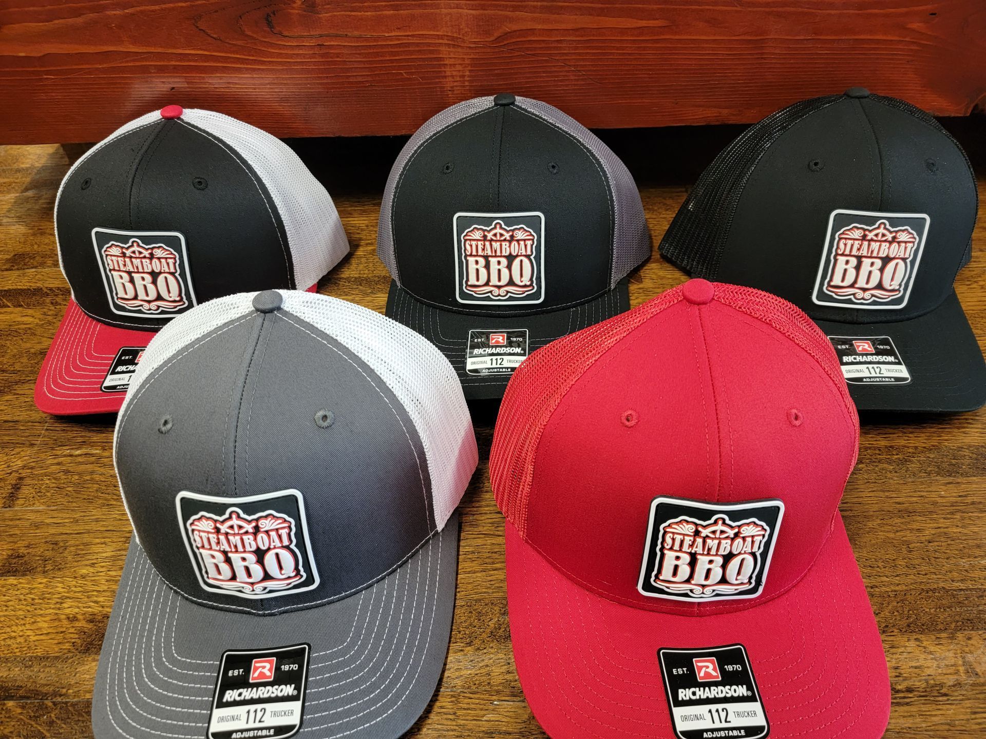 A group of baseball caps are sitting on top of a wooden table.