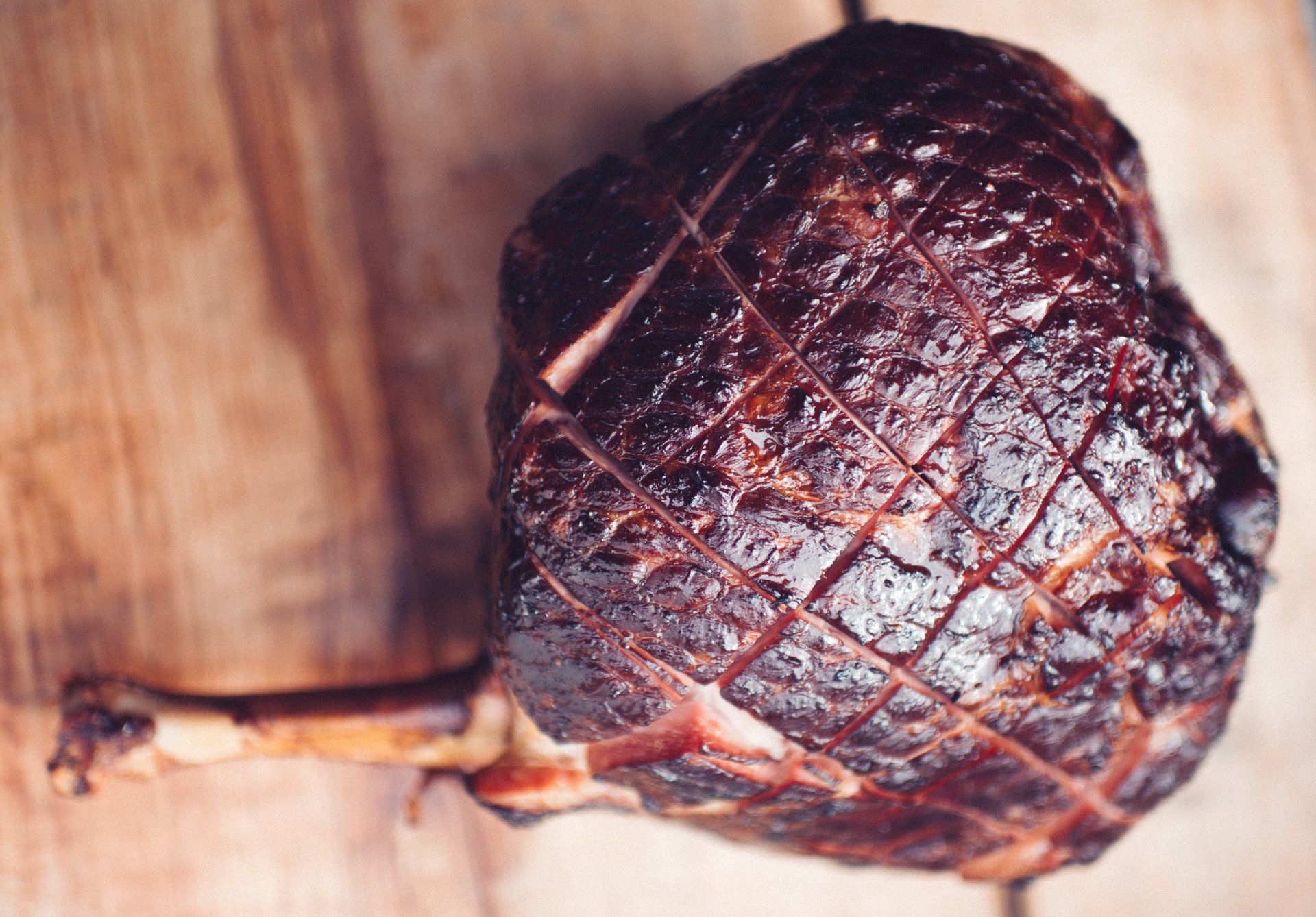 A large piece of ham is sitting on a wooden table.