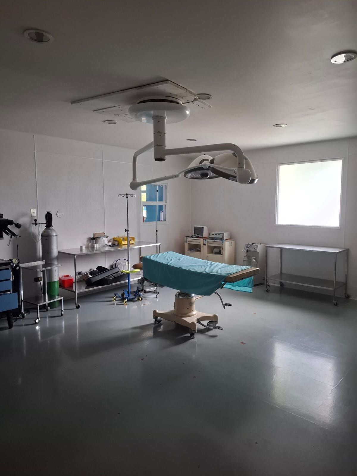 Leerer Operationssaal mit OP-Tisch, OP-Leuchten und medizinischen Geräten.