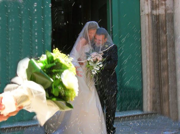Gli sposi ricoperti di coriandoli escono da una chiesa; nelle vicinanze è presente un bouquet nuziale.