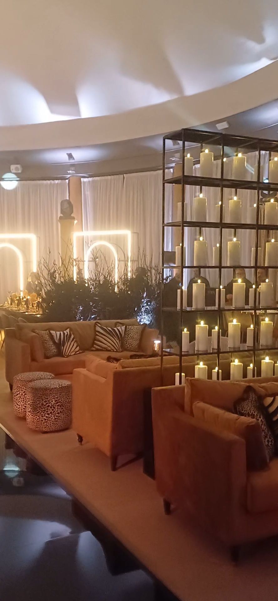 Accogliente lounge con sedute arancioni, candele e uno sfondo decorativo. L'illuminazione calda crea un'atmosfera invitante.