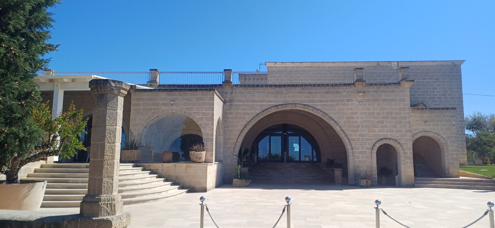 Un edificio in mattoni beige con archi, scale e uno sfondo di cielo azzurro.