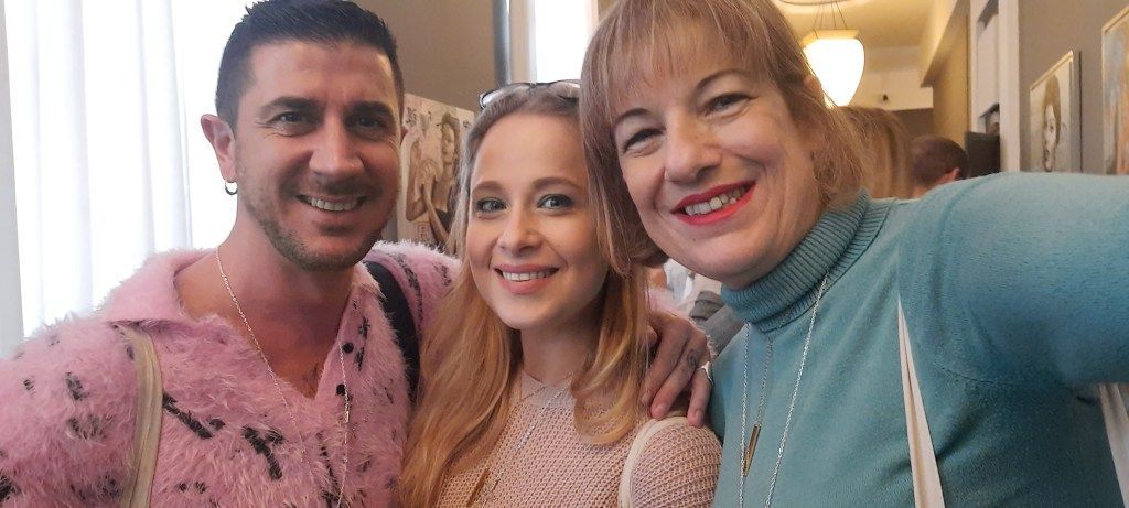 Tre persone sorridenti posano vicine; un uomo e una donna abbracciano una donna più giovane.