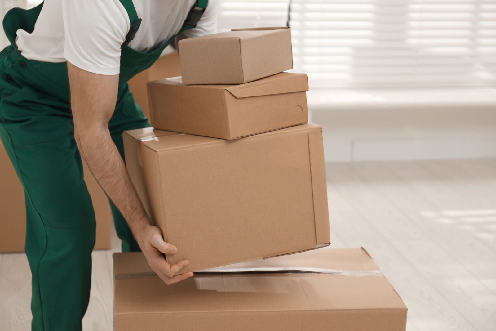 A man is lifting a stack of cardboard boxes.