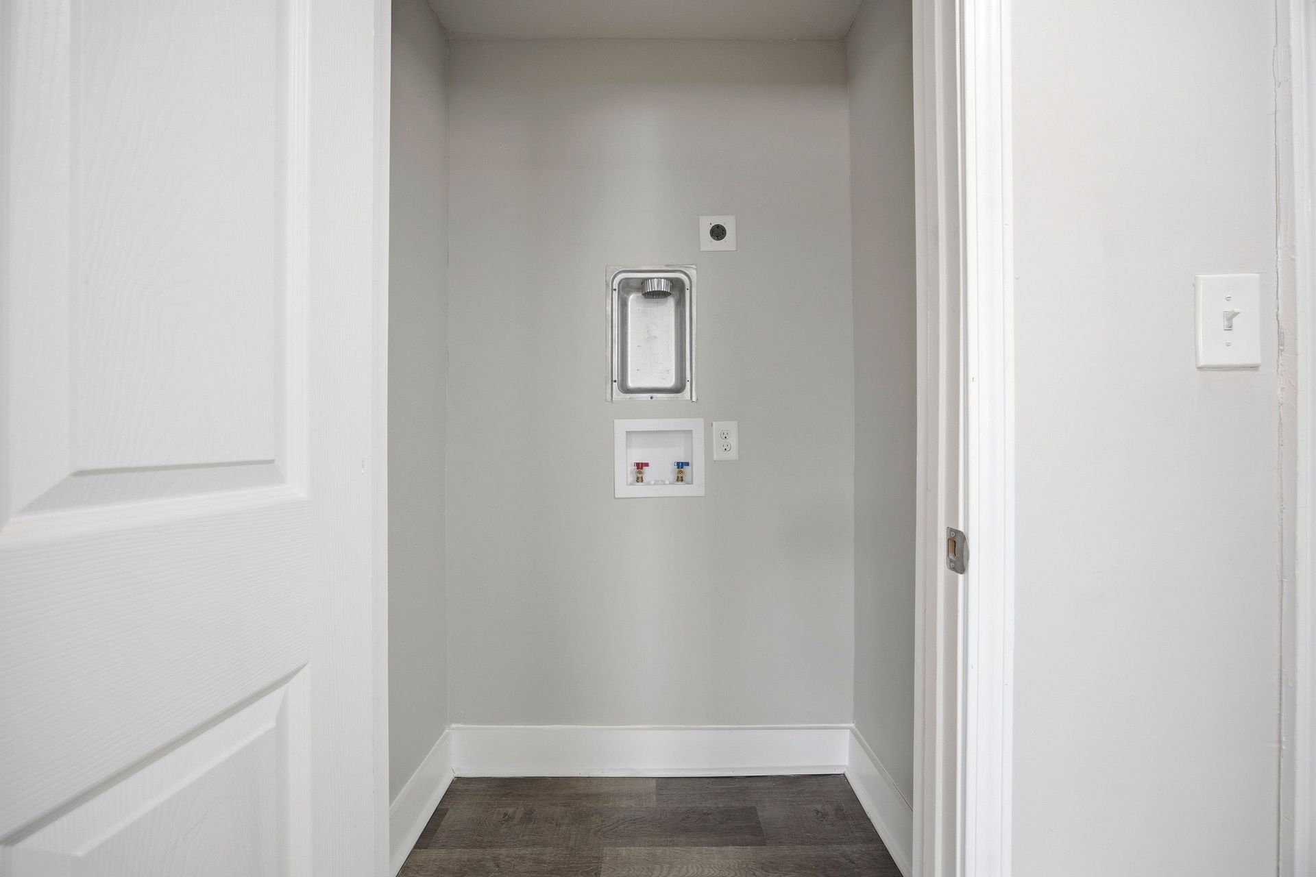 Empty hallway alcove with a recessed wall niche, light gray walls, and white doors.