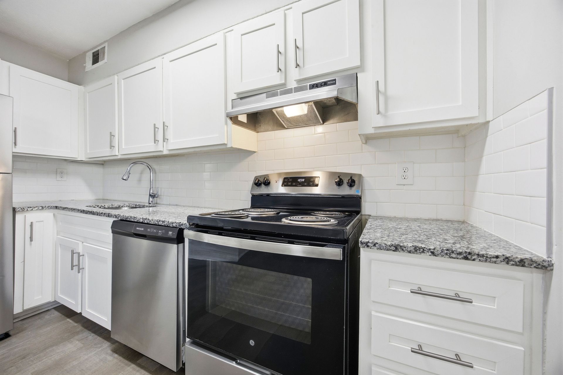Bright white kitchen with stainless steel appliances, granite counters, and white cabinets