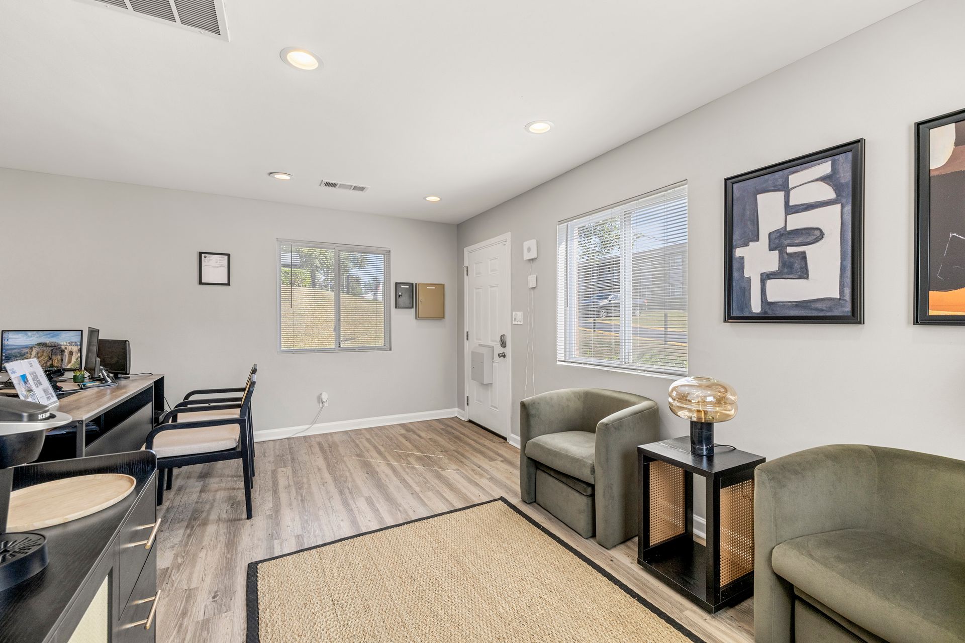 Bright living room with gray chairs, piano, wall art, and large windows