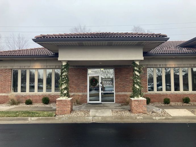 Brick building with a glass door entrance, columns wrapped with garland, topped with terracotta tile roof.