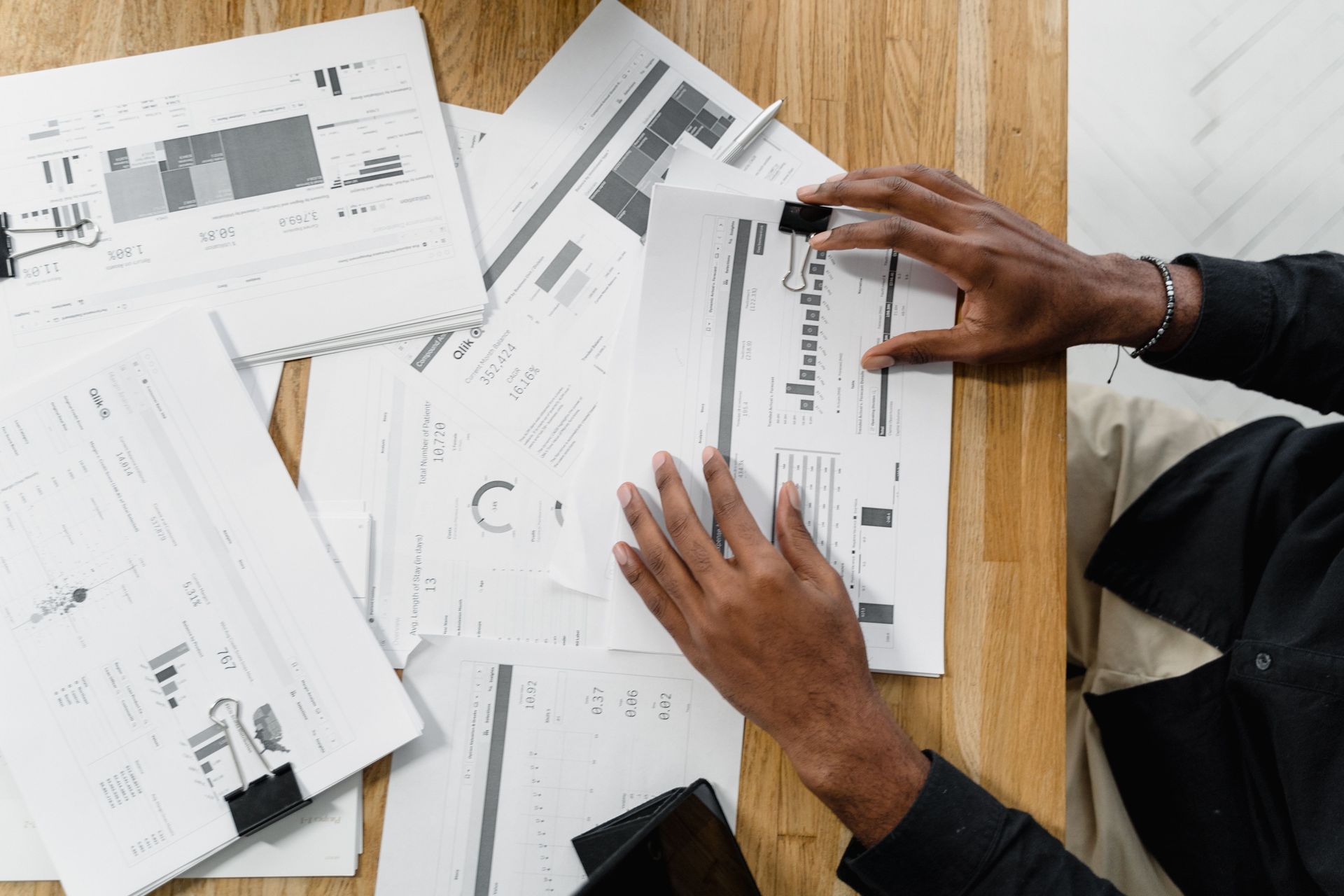 Hands reviewing architectural floor plans spread across a wooden table