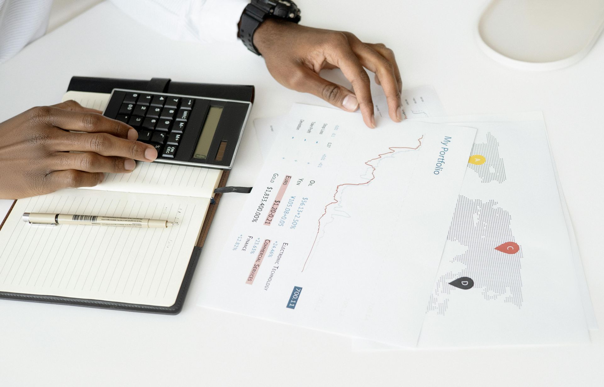 Three businessmen in suits reviewing charts on a tablet, seated at a table.