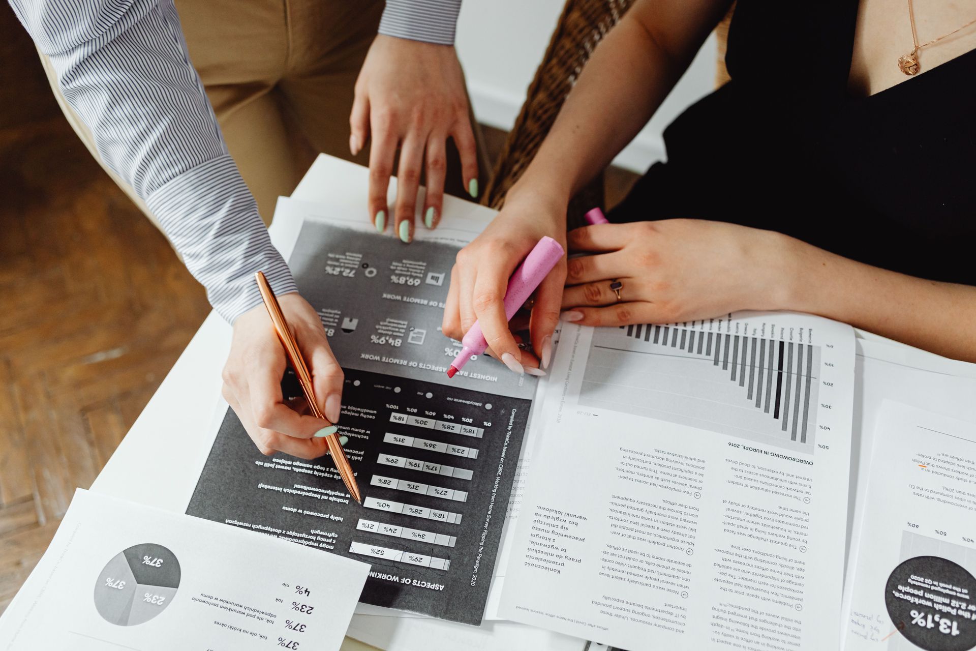 Hands pointing at printed charts and documents on a desk during a team meeting