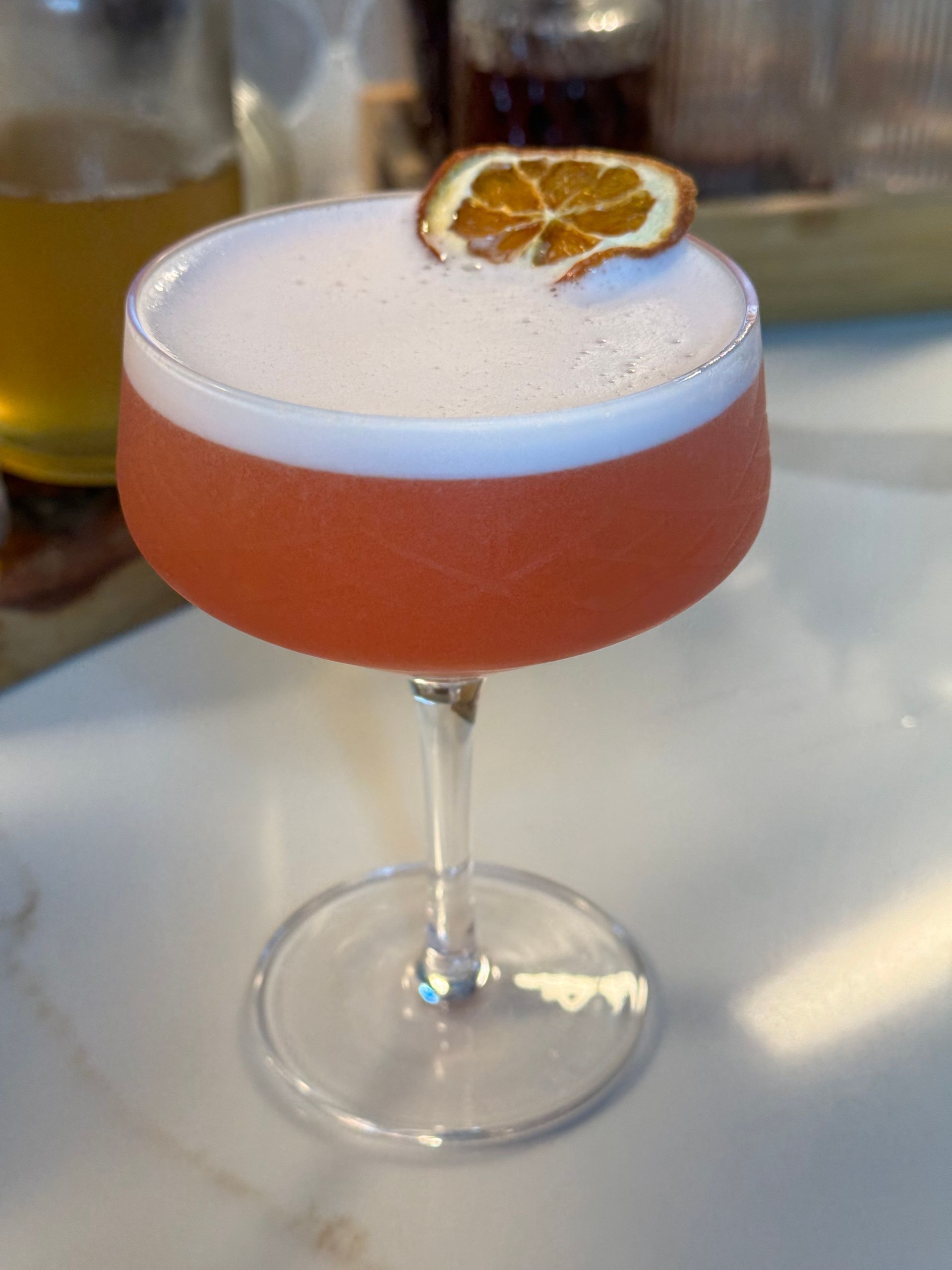 A close up of a cocktail with a slice of orange on top