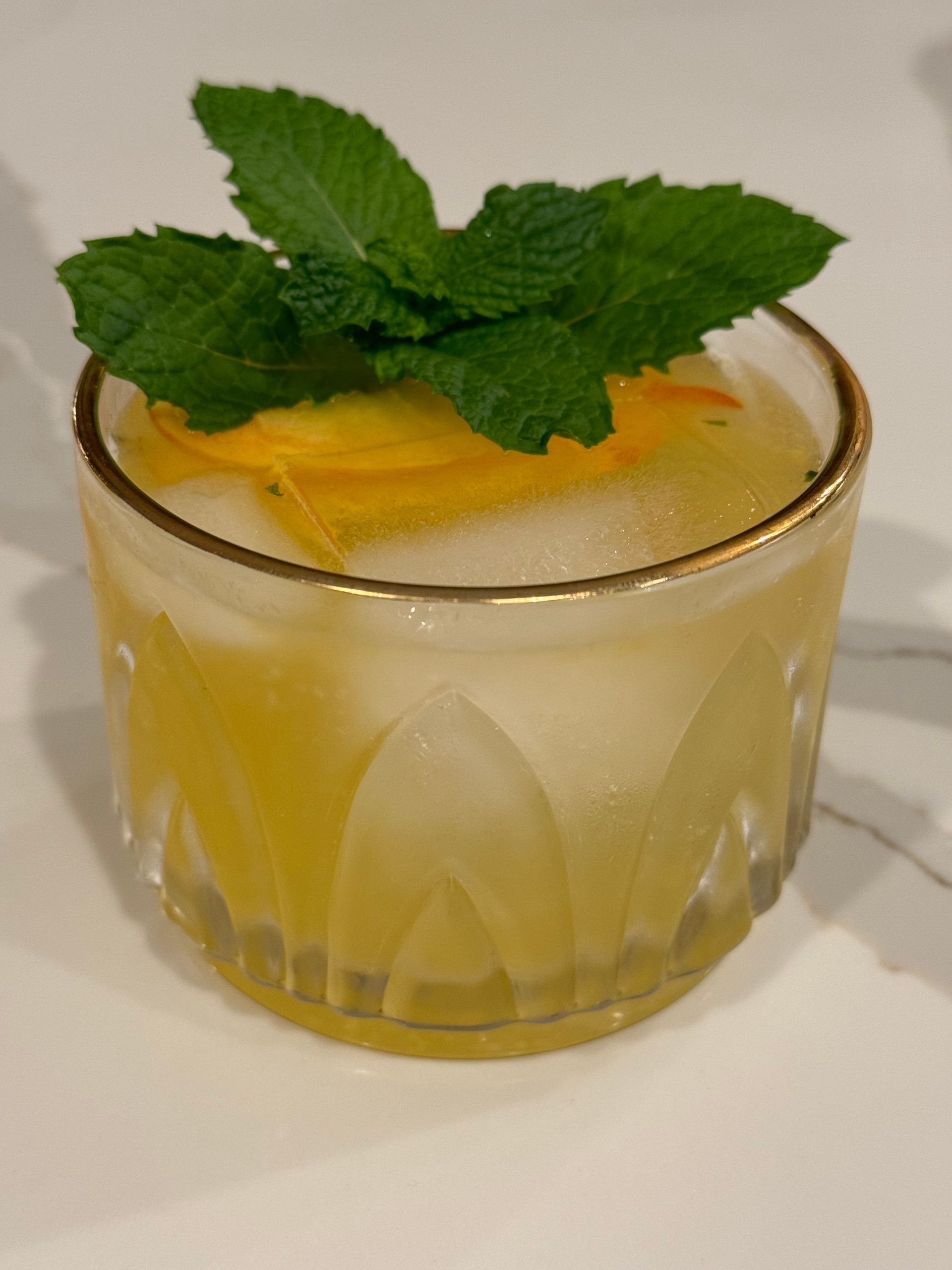 A close up of a drink with mint leaves on top