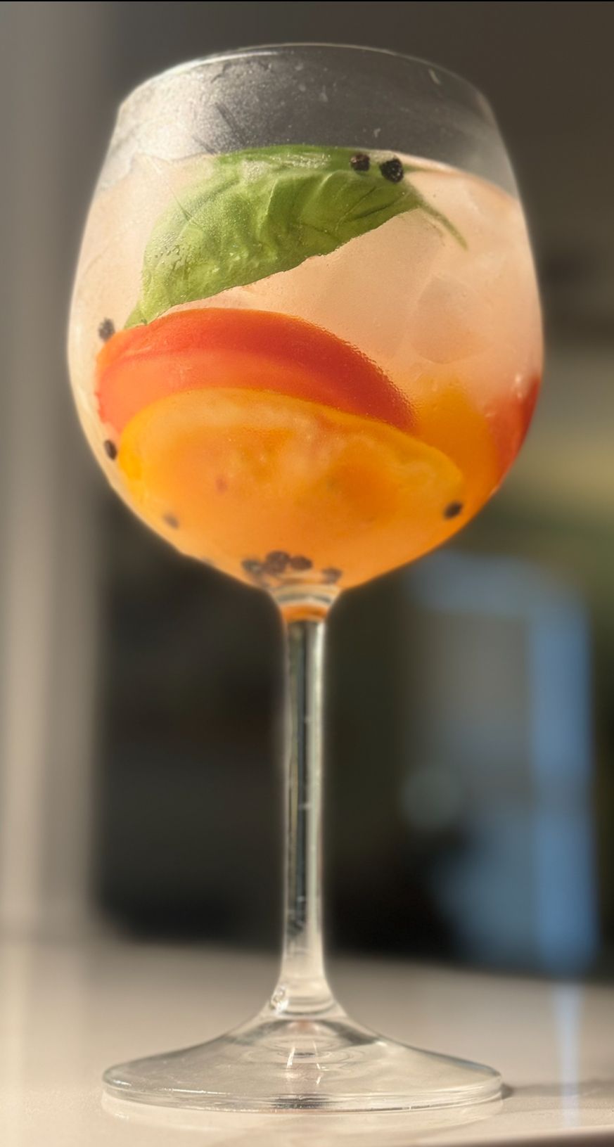 A close up of a wine glass filled with a drink on a table.