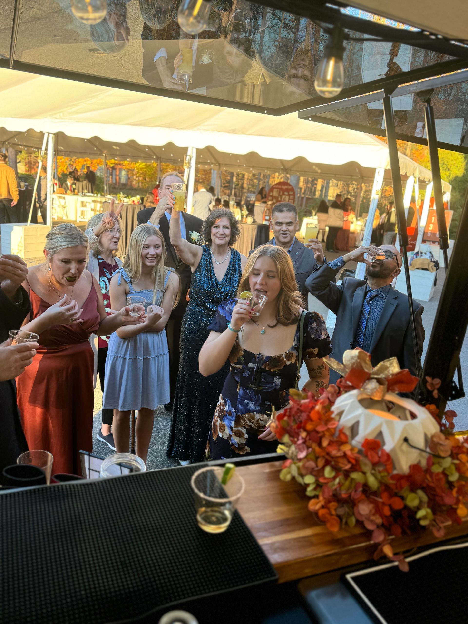 A group of people are standing around a bar drinking wine.