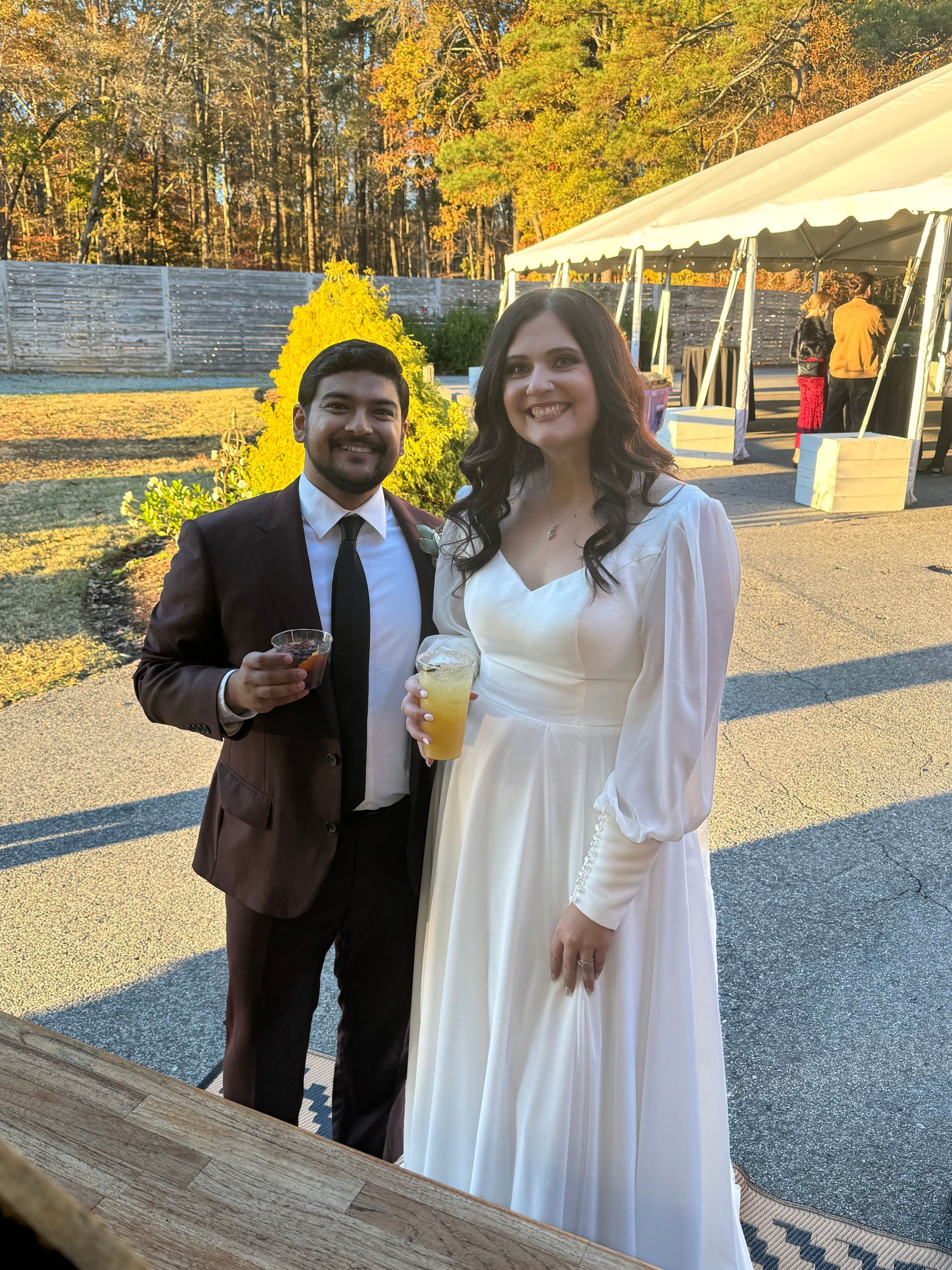 A bride and groom are posing for a picture in front of a tent.