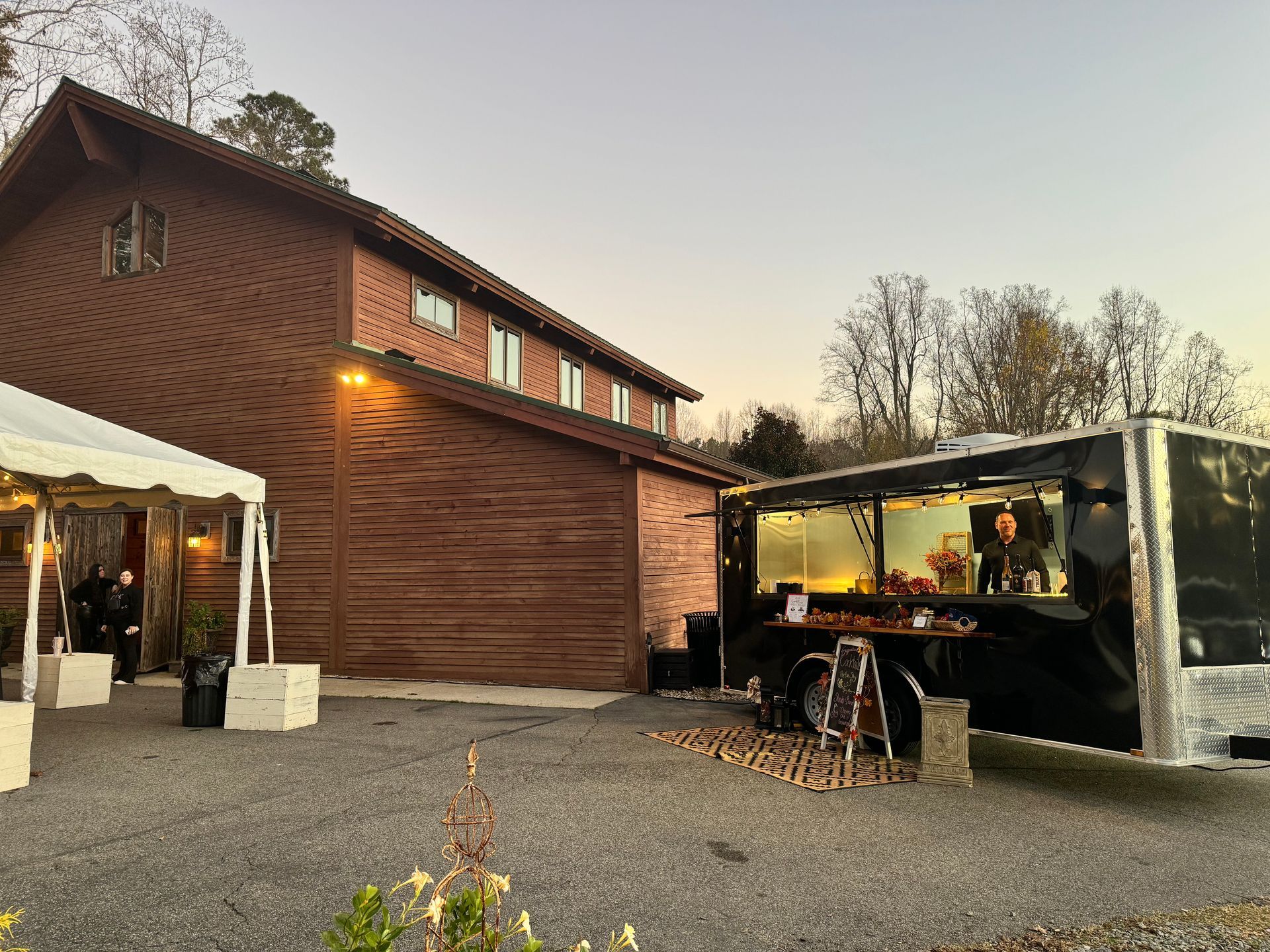 A food truck is parked in front of a large wooden building.