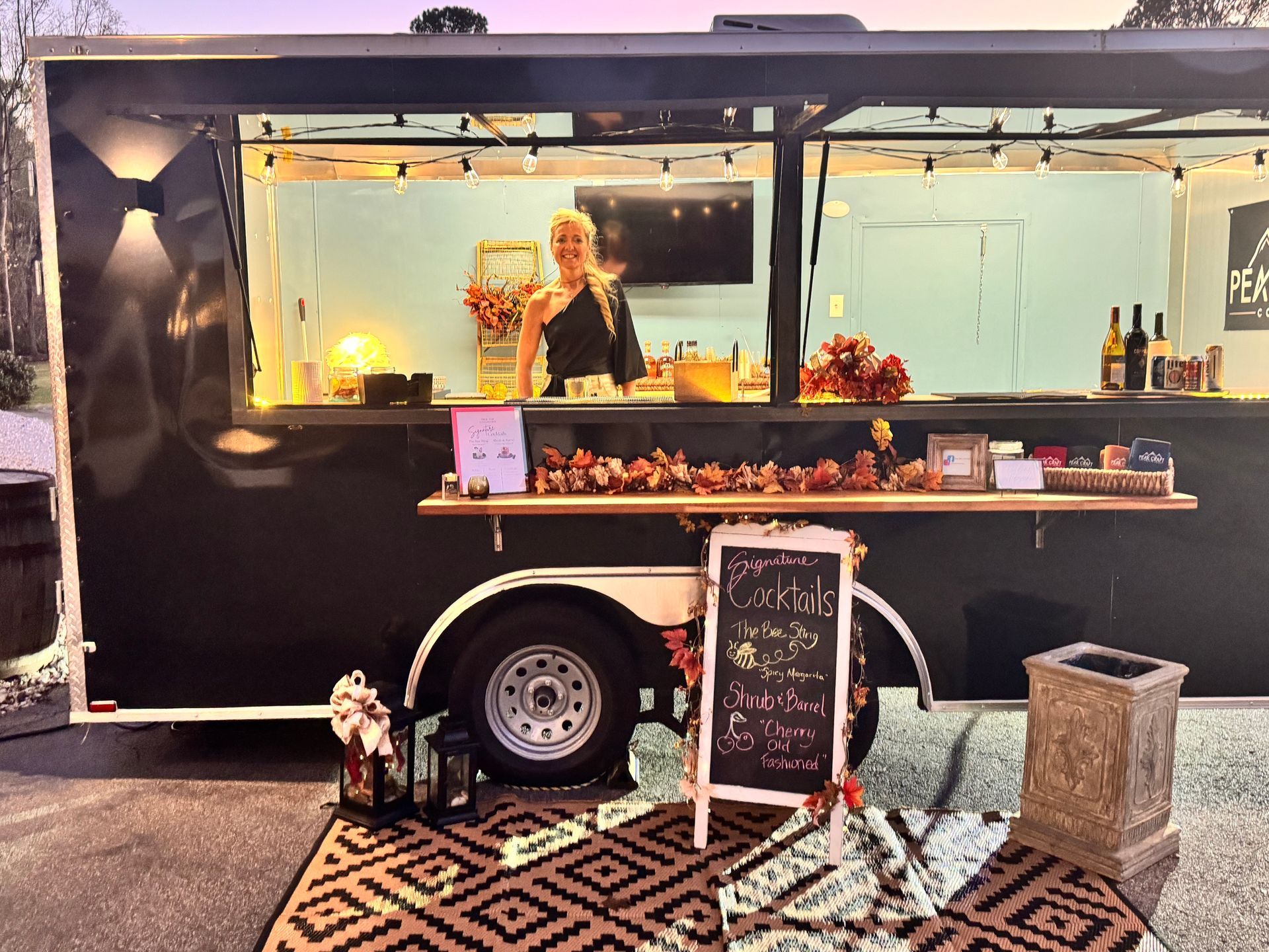 A woman is standing in front of a food truck.