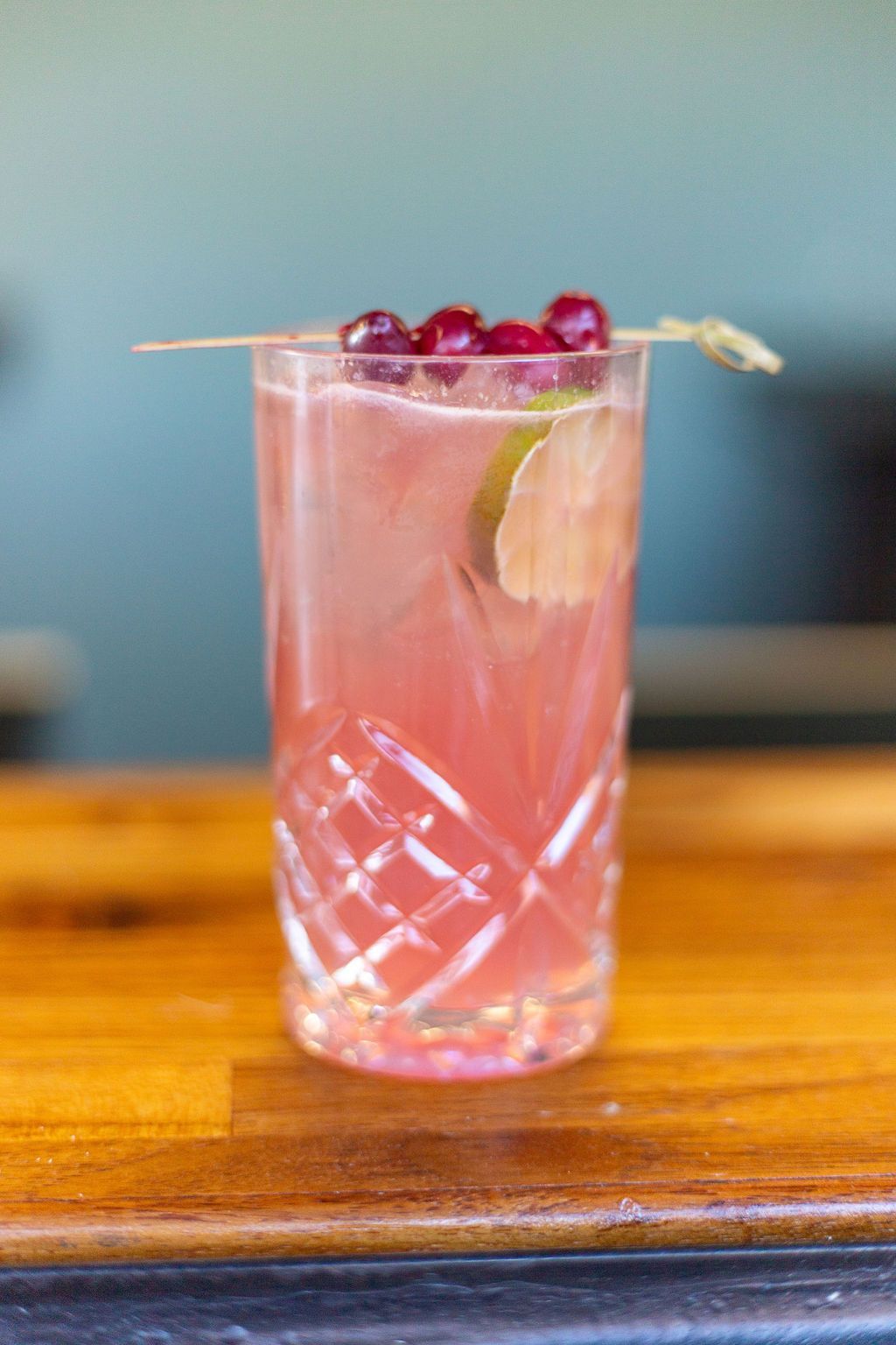 A close up of a pink drink in a glass on a wooden table.
