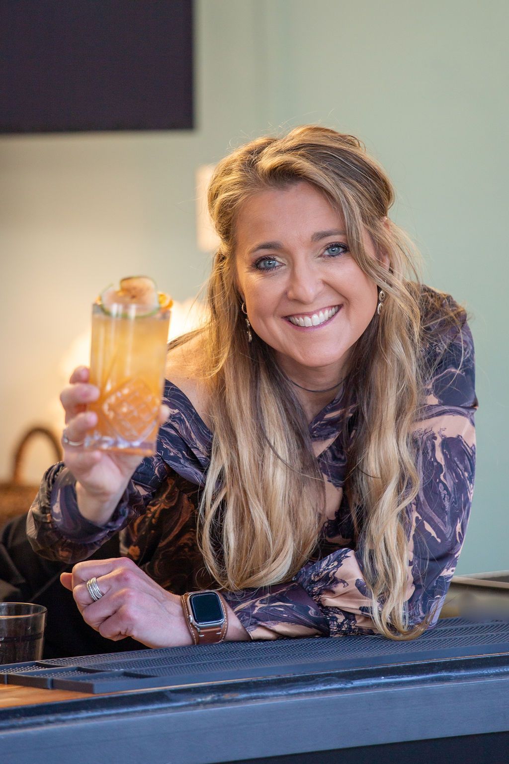 A woman is sitting at a bar holding a drink in her hand.