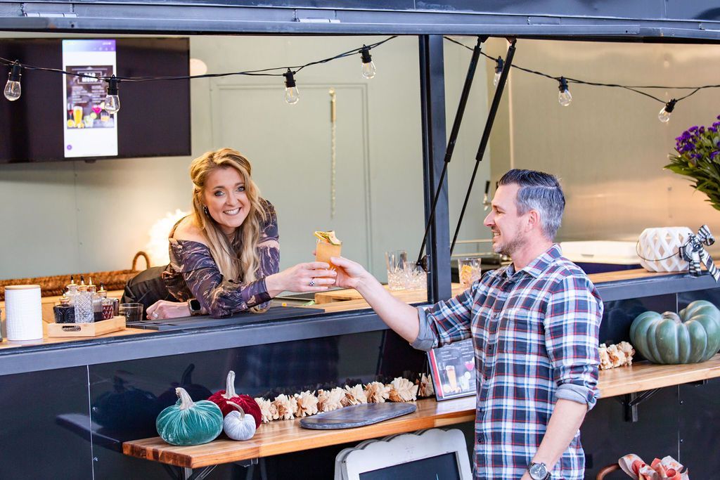 A man is serving a woman a drink at a food truck.