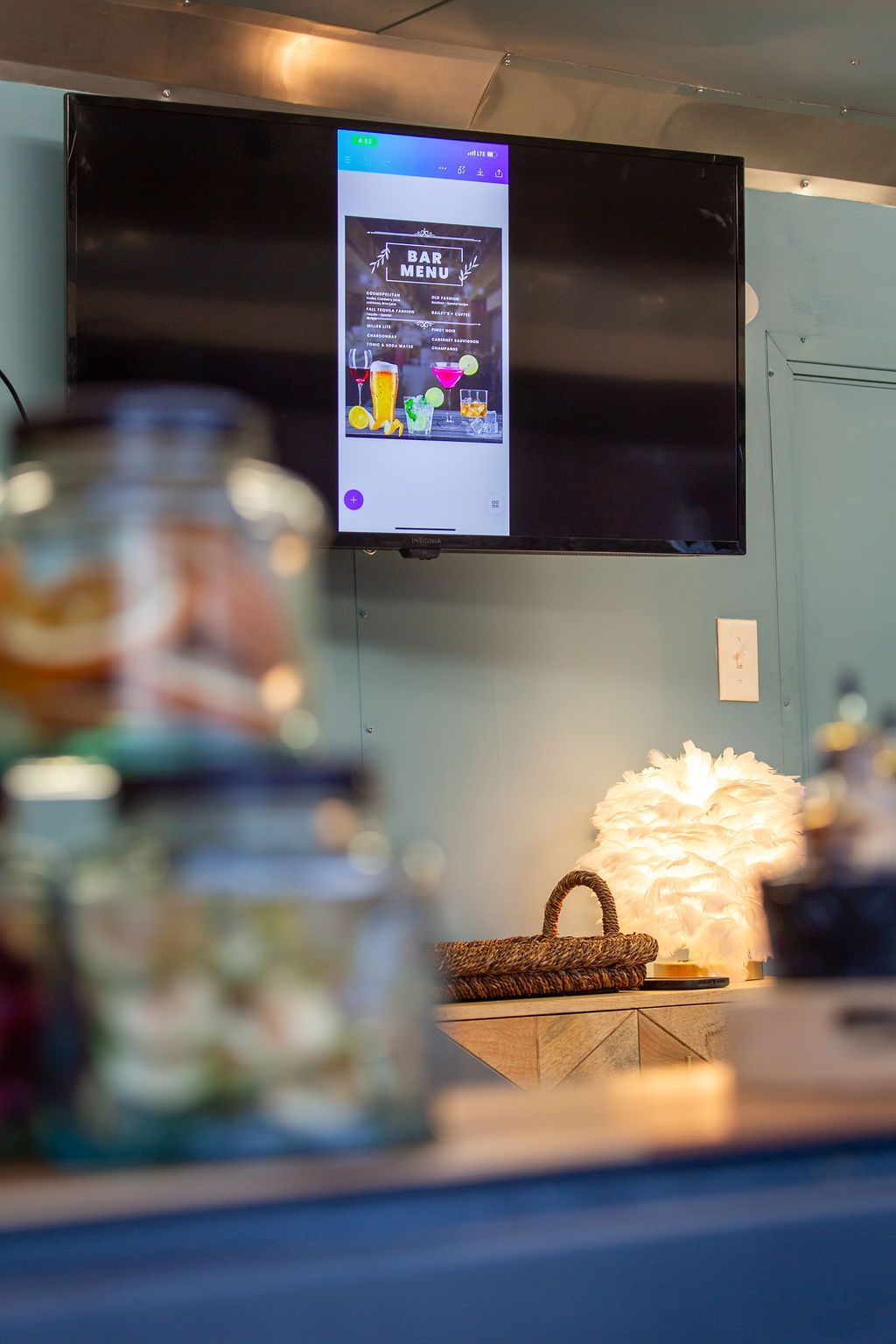 A television is hanging on the wall above a counter in a room.