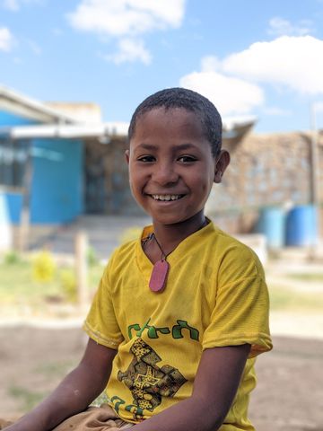 Ethiopian boy wearing a yellow shirt and smiling