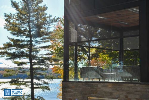 Véranda grillagée donnant sur le lac et ornée d'arbres aux couleurs d'automne.