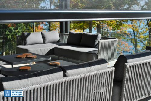 Terrasse ext&eacute;rieure avec canap&eacute;s d'angle gris, balustrade en verre, vue sur le lac et feuillage d'automne.