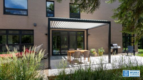 Terrasse avec pergola, table, chaises et barbecue jouxtant une maison moderne en briques.