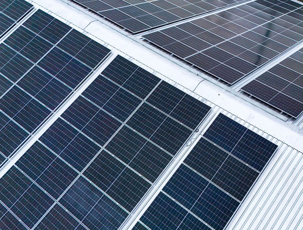 Solar panels on a rooftop, angled in rows against a light-colored roof.