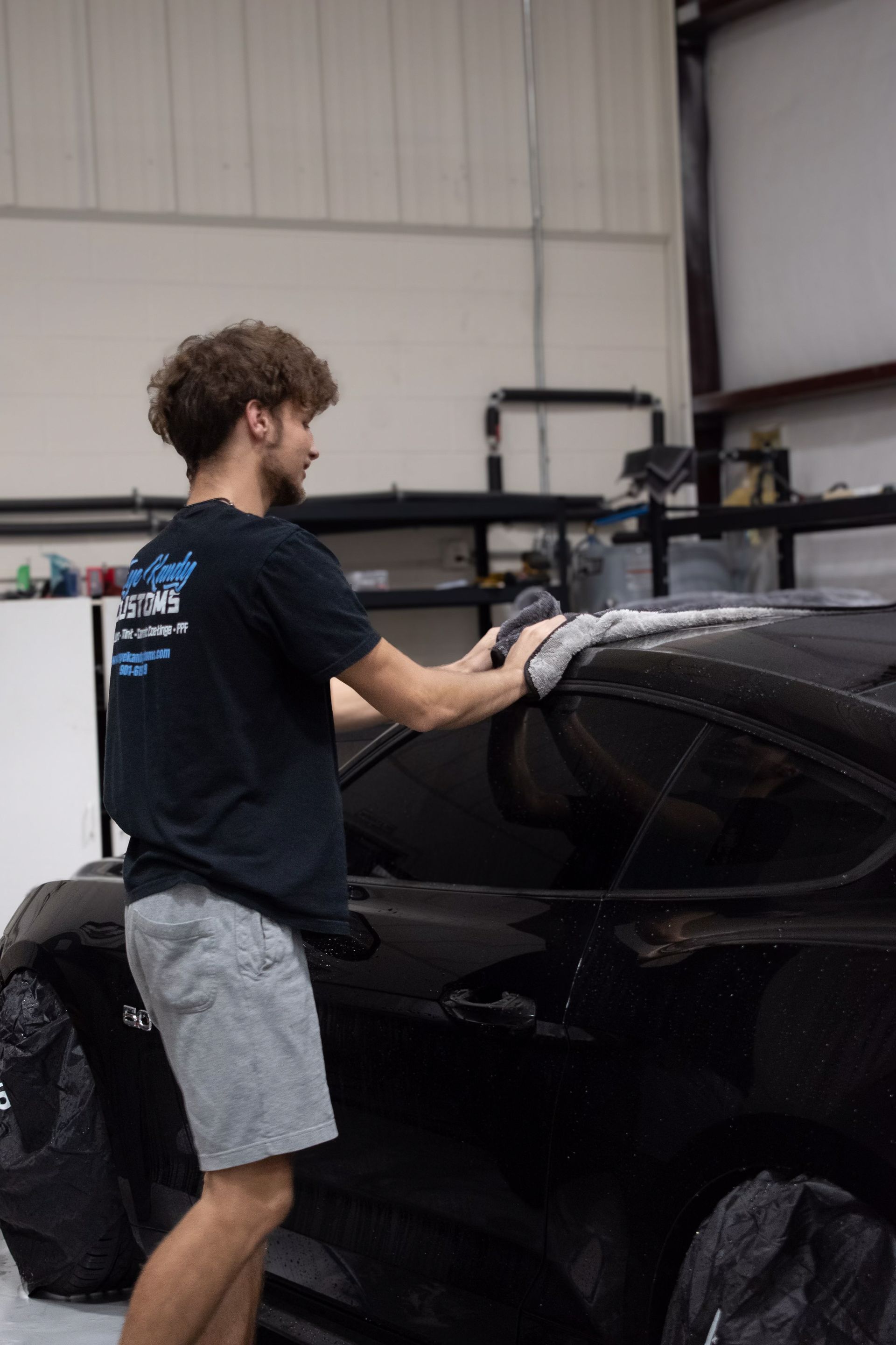 a man is cleaning a car with a towel in a garage .