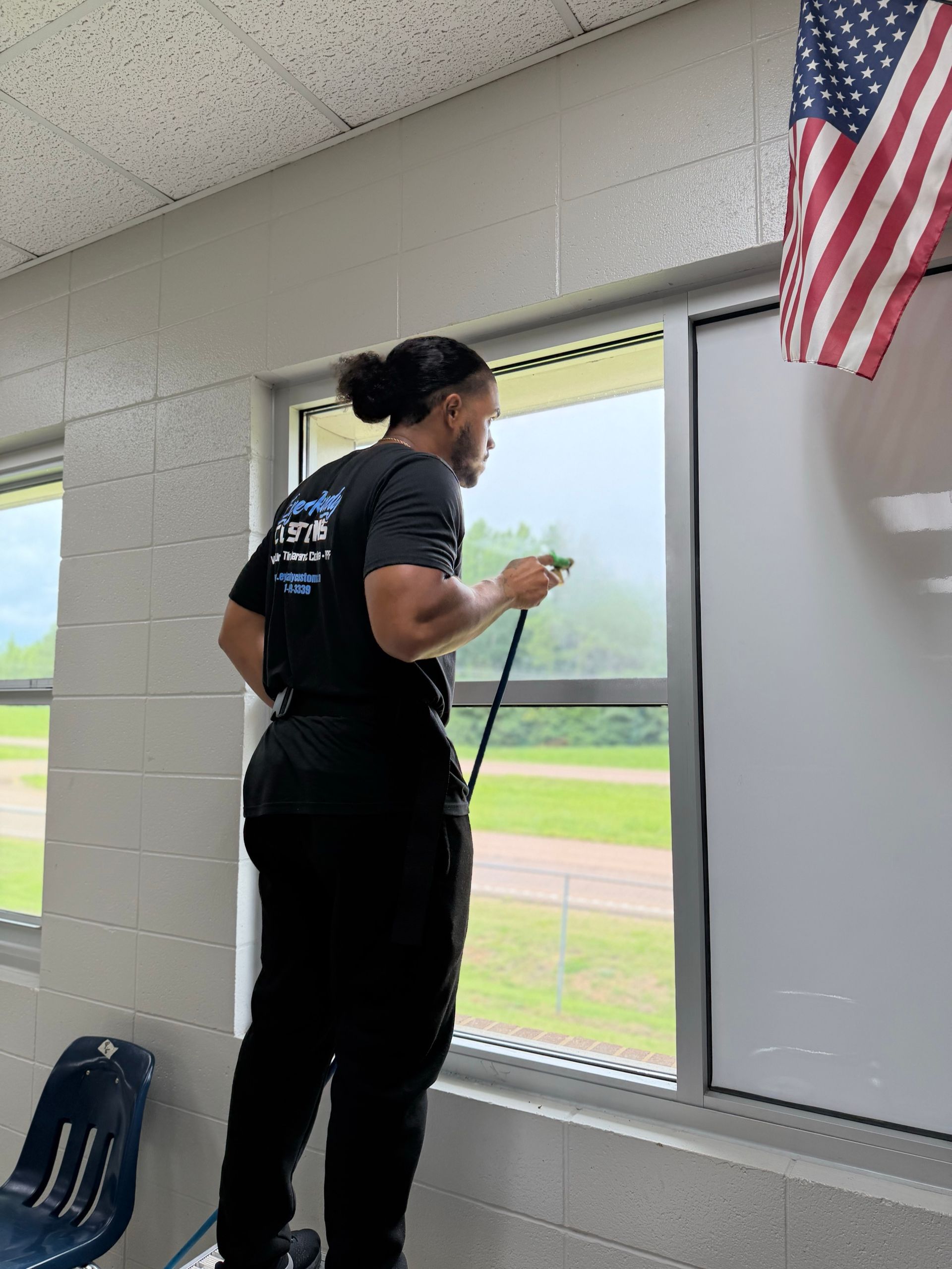 Eye Kandy Customs technician applying window tint film to a classroom window