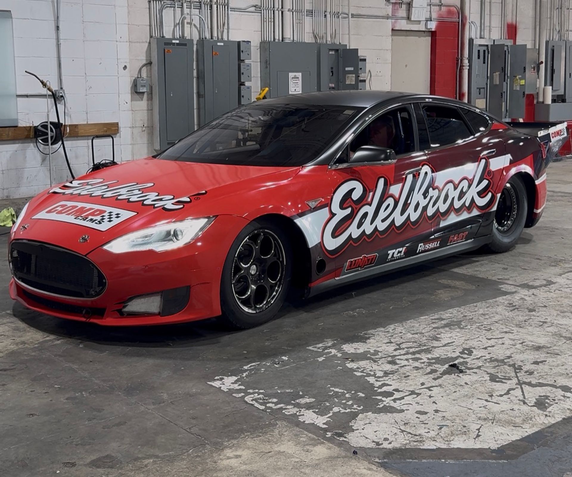 Side view of the red Edelbrock Tesla Model S wrap in the shop