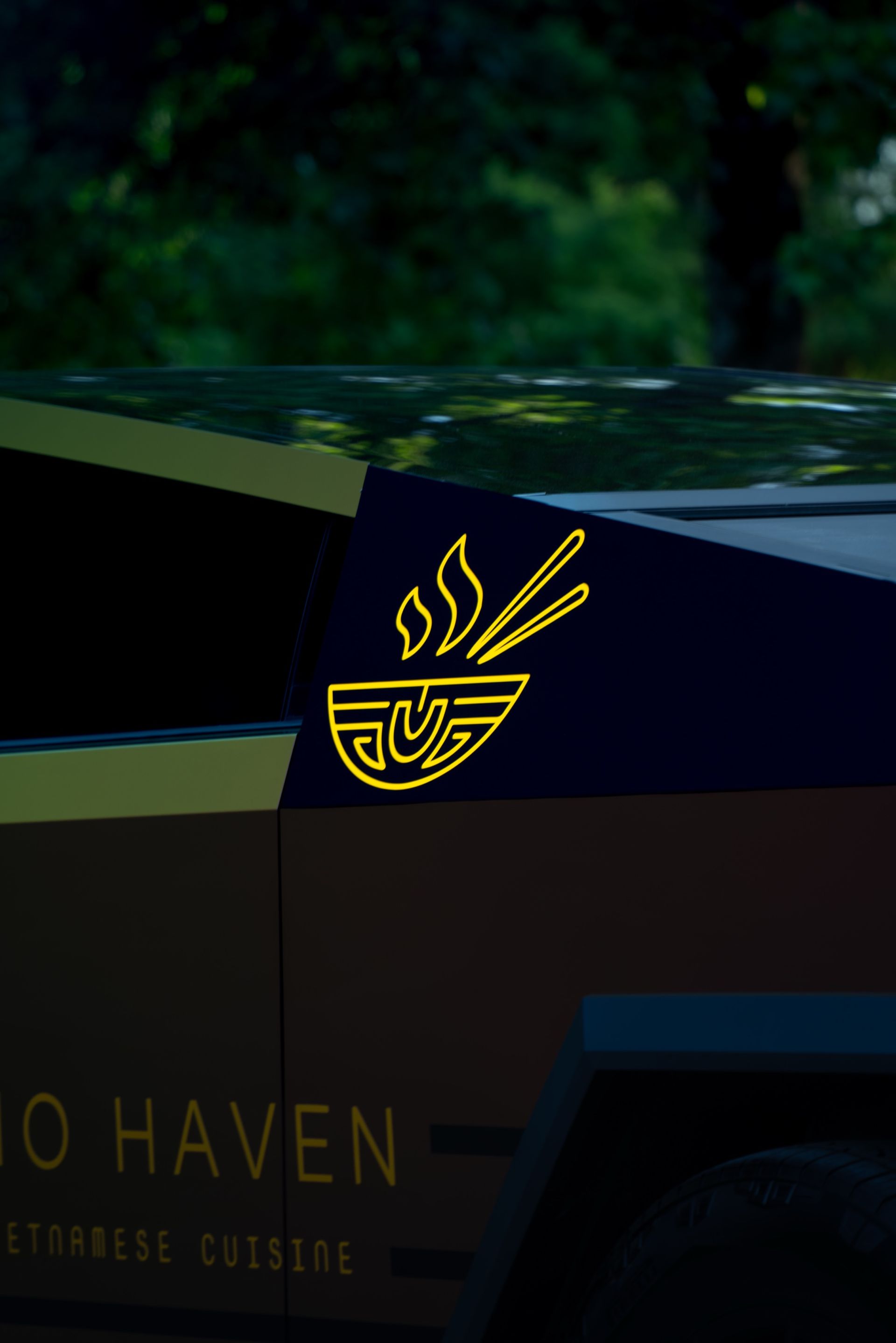 Close-up of the gold chrome Pho Haven bowl logo on the Cybertruck wrap