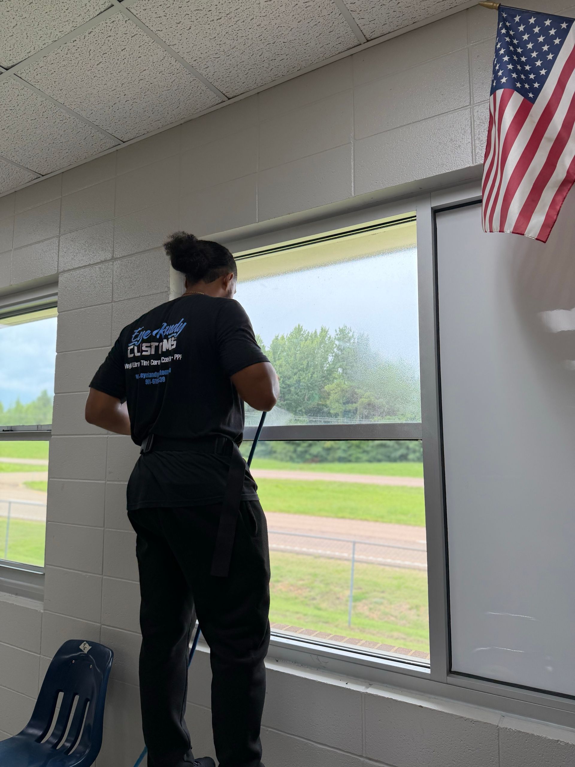 Installer squeegeeing window tint on a classroom window