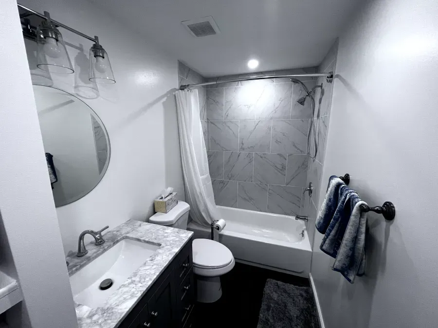 A small modern bathroom with white walls, a shower, and a vanity.