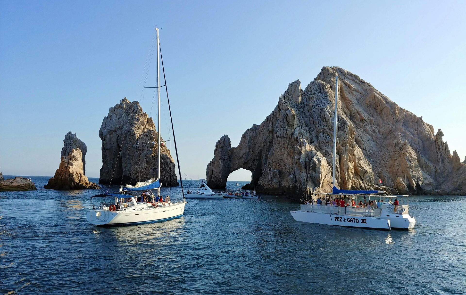 Hay algunos barcos en el agua cerca de una formación rocosa.