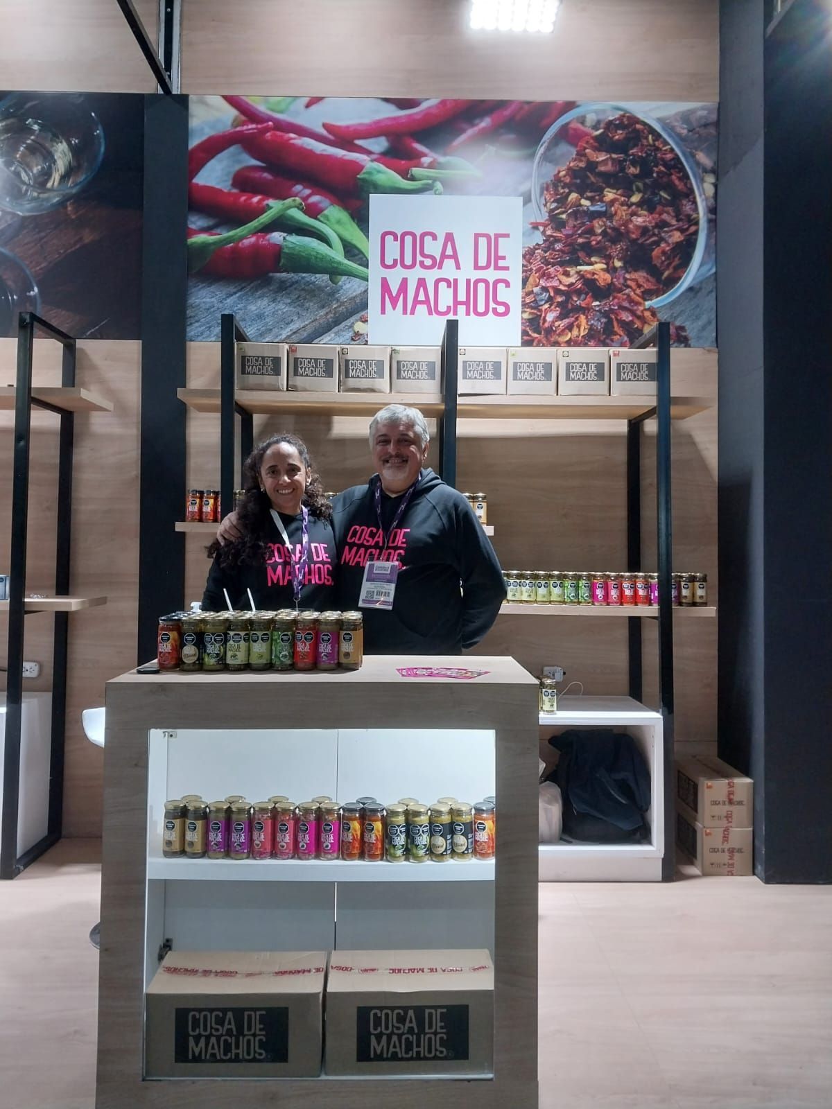Dos mujeres detrás de un puesto de dulces con la etiqueta “Casa de Macios” en un puesto de mercado.