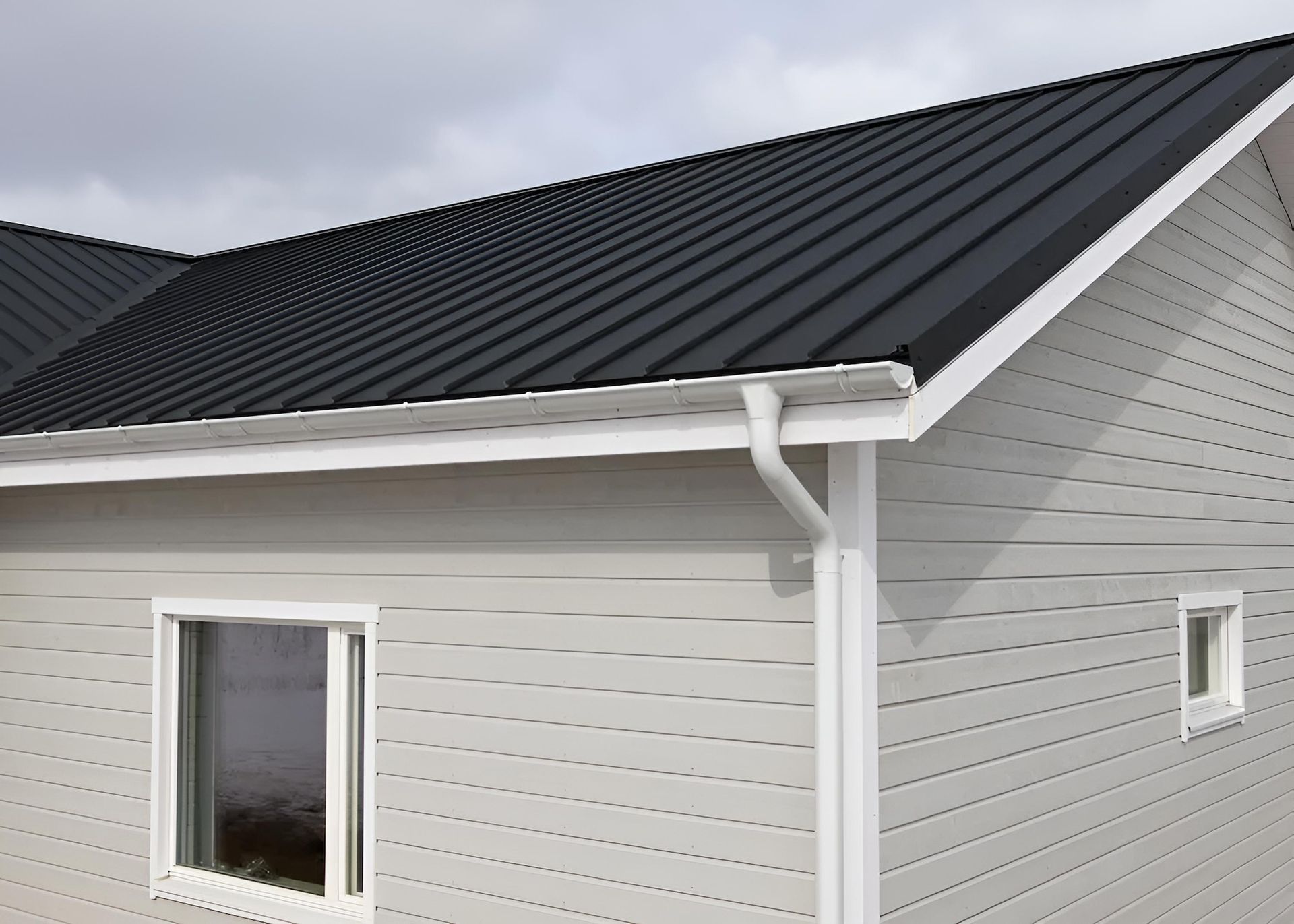 A White House With a Black Roof and White Trim — Ron Nickel Roofing in Labrador, QLD