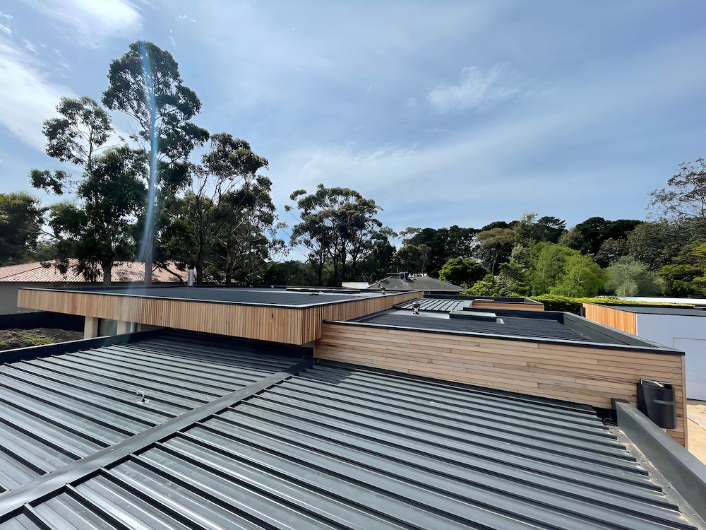 A Roof With a Wooden Deck on Top of It and Trees in the Background — Ron Nickel Roofing in Murwillumbah, NSW