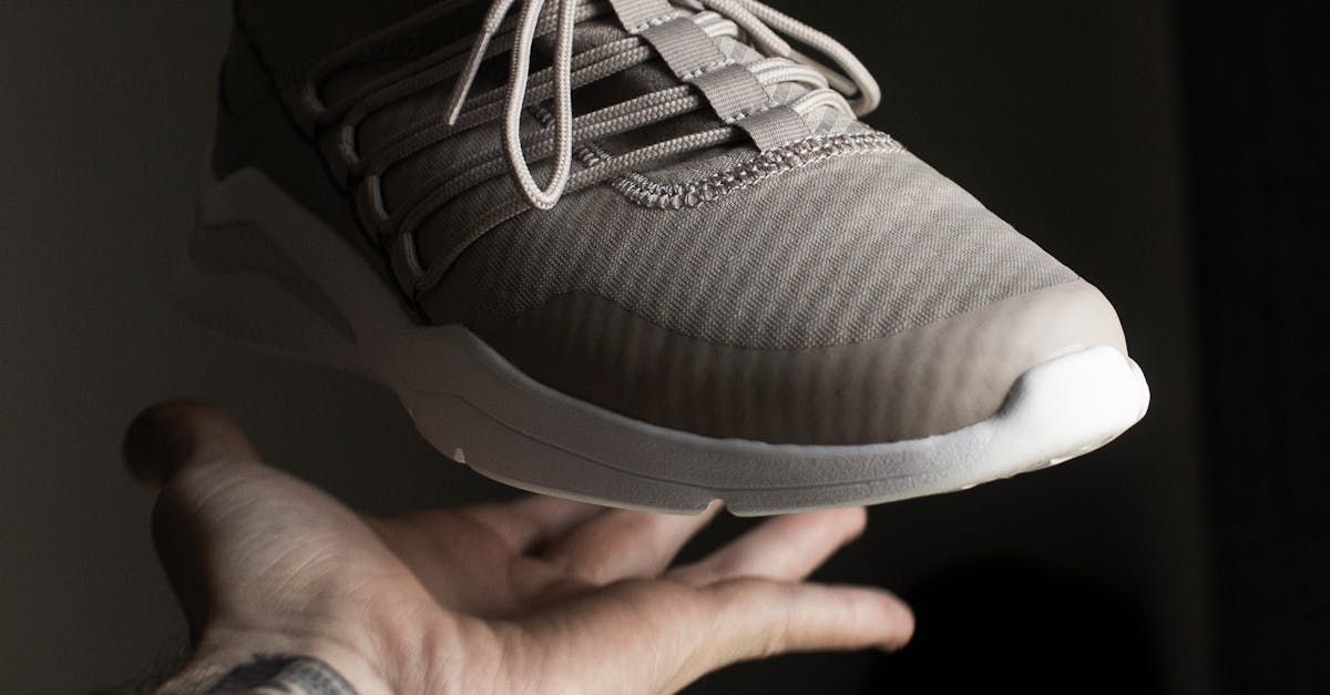 A person is holding a pair of sneakers in their hand.