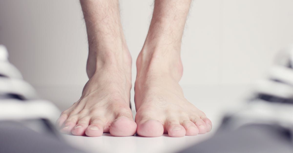 A close up of a person 's bare feet standing next to a pair of shoes.